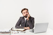 © timtimphoto - Bearded manager sits at the table props his chin with his hand looks to the right side bored doesn't know what to do thinks about something unimportant, dressed in a expensive suit with a tie
