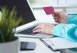 © cameravit - Female office worker hands holding credit card, typing on the keyboard of laptop, online shopping detail close up.