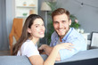 © ty - Portrait of cute young couple sitting in sofa.
