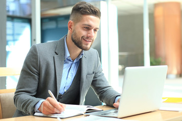 Portrait of young man sitting at his desk in the office.