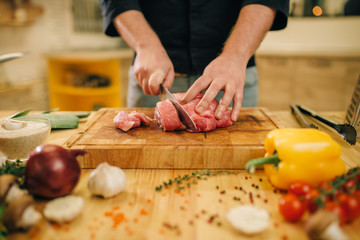 Wall Mural - Male person with knife cuts raw meat into slices