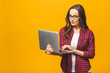 © denis_vermenko - Young happy smiling woman in casual clothes holding laptop and sending email to her best friend. Isolated against yellow background.