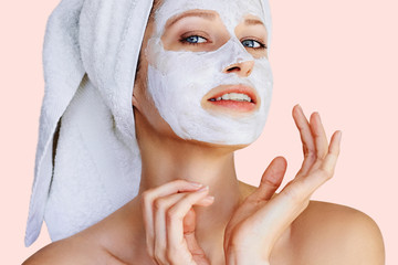 Beautiful young woman with facial mask on her face. Skin care and treatment, spa, natural beauty and cosmetology concept.