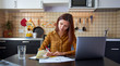 © EverGrump - Portrait of a worried young woman sitting in the kitchen looking at bills and thinking how to pay all the debts for rent and study. A woman writes important thoughts on a piece of paper