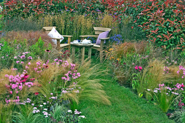Wall Mural - Corner of a cottage garden with outdoor eating and a display of grasses and flowers