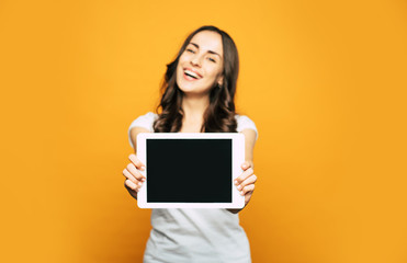 Wall Mural - A screen of a white tablet PC which is placed in hands of  a nice and happy woman with pleasant appearance and cool casual outfit.