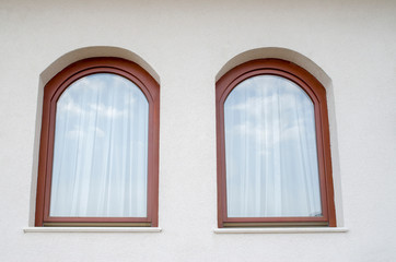 Two wooden arched windows with thin seamless curtain