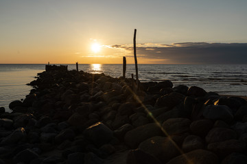 Boulder beach pier sunset with vivid red and orange colors on the Baltic Sea - Tuja, Latvia - April 13, 2019