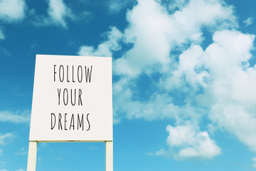 Wall Mural - sign against blue sky with clouds with the text – follow your dreams