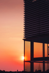 Wall Mural - Glass architecture facade with lamella structure on a park deck roof top with sunset light trough the transparent glass and warm color tones. Modern building design. Old town of Braunschweig, Germany