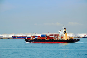 Container ship departing from Singapore industrial area.