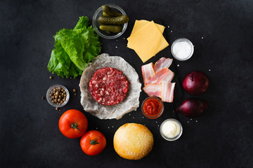 Wall Mural - Top view and flat lay of burger ingredients and sauce on black table with copyspace. Burger food background