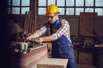 Canvas Print - Carpenter working on woodworking machines in carpentry shop 