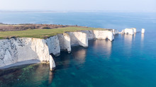 An Aerial View Of The Old Harry Rocks Along The Jurassic Coast With Crystal Clear Water And White Cliffs Under A Hazy Sky