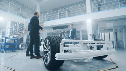 Wall Mural - Team of Automobile Design Engineers Enter Automotive Innovation Facility. Start Working on Electric Car Platform Chassis Prototype that Includes Wheels, Suspension, Hybrid Engine and Battery.