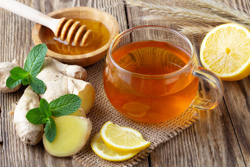 Wall Mural - A glass cup of tea with lemon, mint, ginger and honey on wooden rustic table.