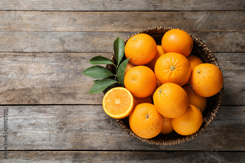 Obraz pomarańcze  wiklinowa-miska-z-dojrzalymi-pomaranczami-na-podloze-drewniane-widok-z-gory-miejsce-na-tekst