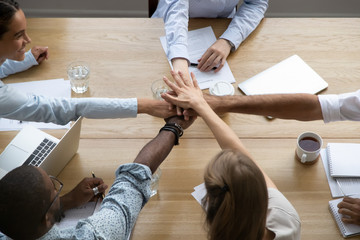 Poster - Team people stacking hands together over table engaged in teambuilding