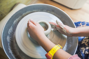 young potter hands working with clay on pottery wheel