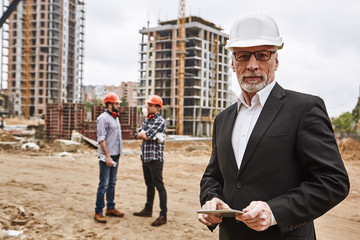 visiting construction site. portrait of confident elderly construction engineer in classic suit and 