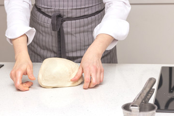 Baking concept. Hard working women prepares pastry by himself, kneads dough on wooden counter with flour and rolling pin. Women cook bakes bread or delicious bun or pasta