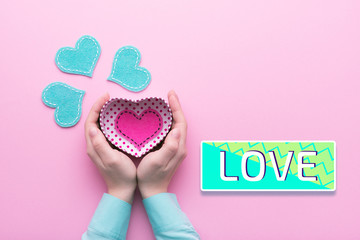 Person holding a present for Saint Valentine's day in his hands. Beautiful colorful background to st. Valentine day. Greeting card with red hearts. Wedding's invitation. Love expression. 