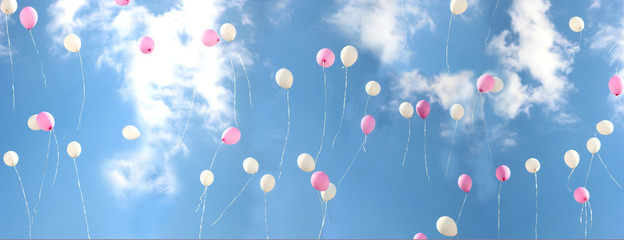 Colorful bouncing balls outdoors against blue sunny sky. Banner