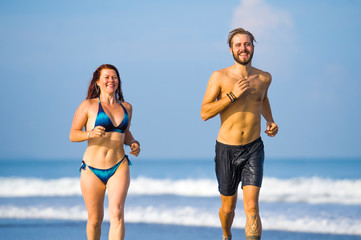 Wall Mural - beautiful couple enjoying Summer holidays travel or honeymoon trip together in tropical paradise beach having fun running carefree and playful on the sea