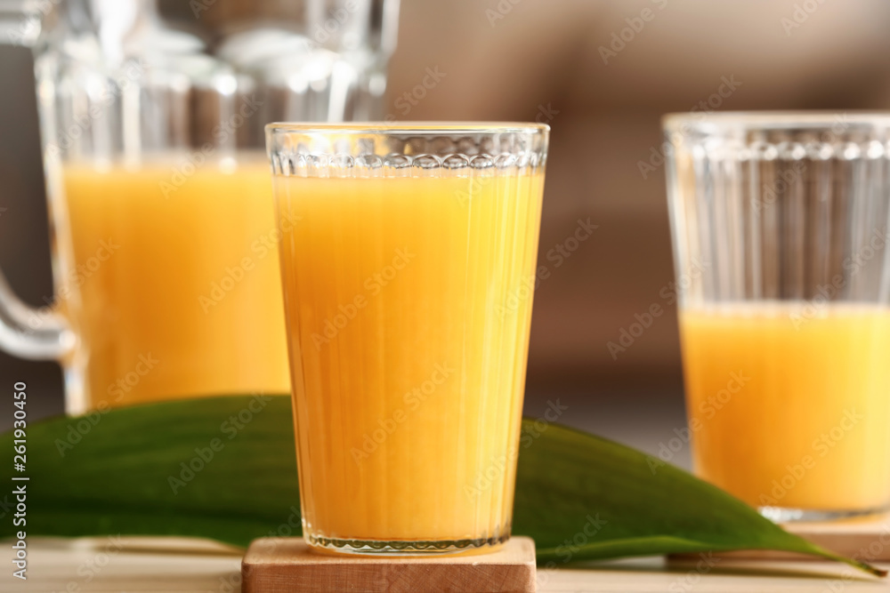 Glass of tasty orange juice on table