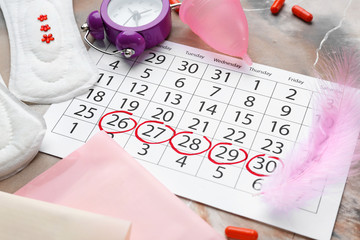 Wall Mural - Menstrual calendar with feminine products, pills and alarm clock on grey background