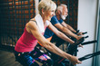 © NDABCREATIVITY - Happy fit mature woman and man cycling on exercise bikes to stay healthy