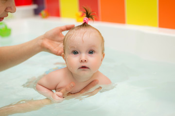 Wall Mural - infant swimming,Mother teaching baby to swim in water pool,Little baby's first swim 