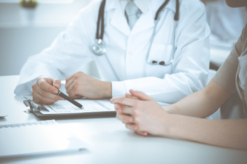 Doctor man and patient are discussing something, just hands at the table. Medicine and health care concepts