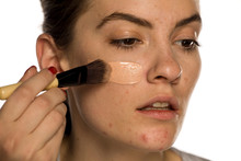 Young Freckled Woman Applying Liquid Foundation On White Background