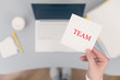 © flowertiare - Woman clerk sitting holding note paper sticker with team word. Business concept. Concept.