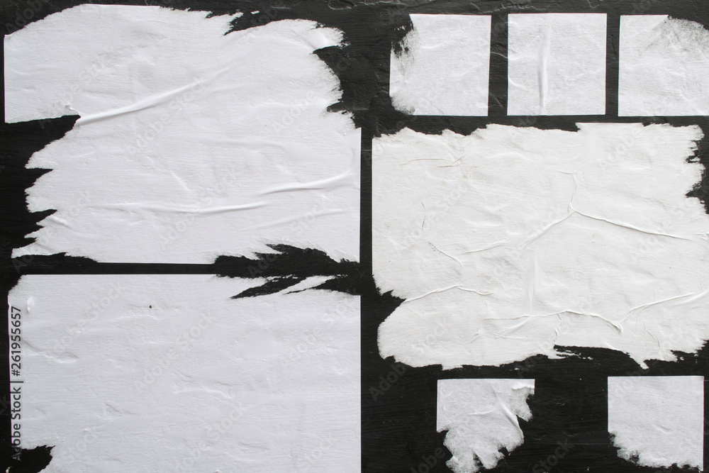Several sheets of white paper pasted on a black wall. - obrazy, fototapety, plakaty 