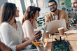 © gstockstudio - Happy business partners. Group of young modern people in smart casual wear discussing something and smiling while working in the creative office