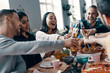 © gstockstudio - Friendship that lasts forever. Group of young people in casual wear toasting each other and smiling while having a dinner party indoors