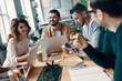 © gstockstudio - Sharing opinions. Group of young modern people in smart casual wear discussing something and smiling while working in the creative office