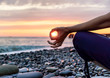 Silhouette of woman in position lotus, practicing yoga and meditating on the beach at sunset