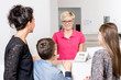 © coldwaterman - Lächelnde Zahnarzthelferin, nimmt die Versichertenkarte von einer Mutter mit ihren Kindern entgegen