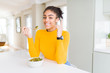© Krakenimages.com - Young african american woman eating healthy green vegatables surprised with an idea or question pointing finger with happy face, number one