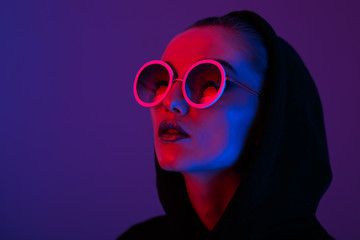 portrait of fashion young girl in a black sweater with a hood and round sunglasses in red and blue n