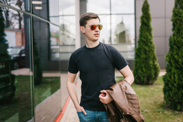 Wall Mural - A stylish man in a black T-shirt. Street photo