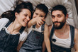 © Ivan - Happy family making selfie on bed. Look at camera. Parents spending free time with their son. Fum moment
