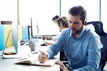 Wall Mural - Happy young male customer support executive working in office.