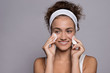 © Halfpoint - A portrait of a young woman cleaning face in a studio, beauty and skin care.
