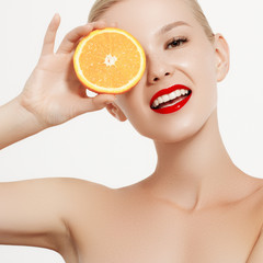 Smiling girl with fresh fruits. Beauty model takes juicy oranges. Joyful girl with freckles. The concept of a healthy diet. Professional make up. Orange slice