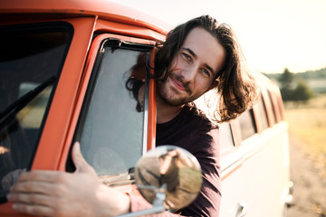 A young man driving a car on a roadtrip through countryside.