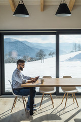 Wall Mural - A mature man sitting at the table in new home, using tablet.